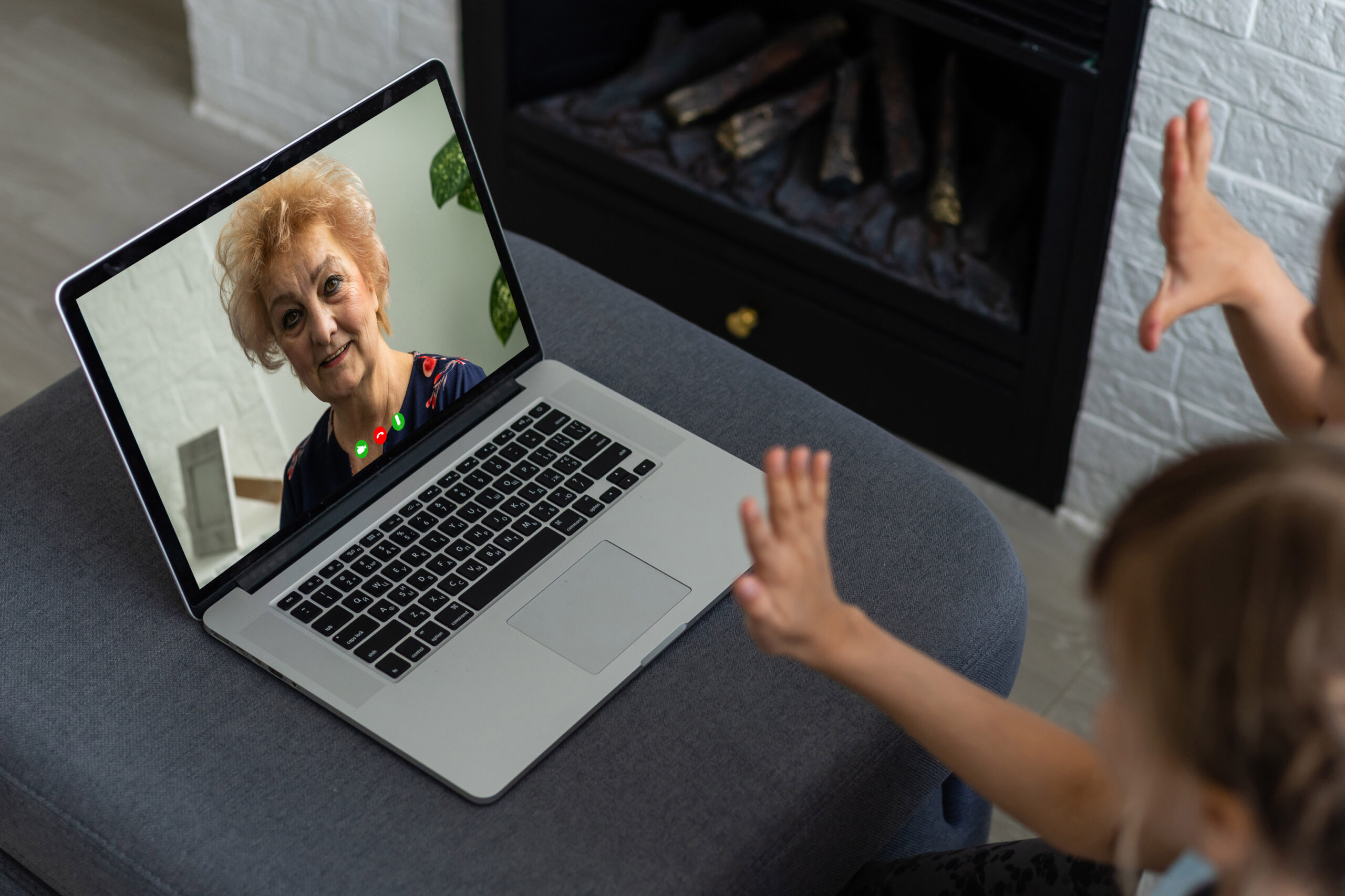 Toddler raising hands, not looking at grandmother during a laptop video call
