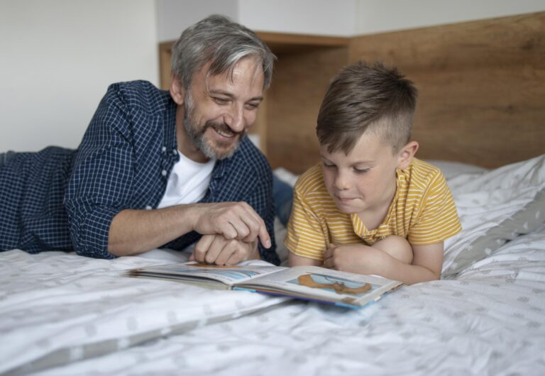 Father reading a bedtime story to his young son on the bed